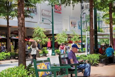 downtown Silver Spring MD with man on park bench in foreground and people walking on pedestrian path in the background